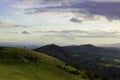 Two people silhouetted in the distance looking from the top of a hill on a sunny winters days. Malvern Hills, England