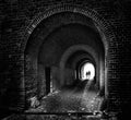 two people silhouettes are walking together like a couple through an old dark brick tunnel to the light, future concept in black Royalty Free Stock Photo