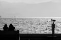 Two people sitting on the bench against the sea view at the seaside and viewing binoculars Royalty Free Stock Photo