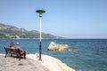 Two people sitting on a bench at Kokkari beach.