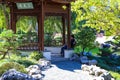 Two people sitting in a Japanese temple in the park surrounded by lush green trees and plants