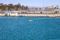 Two people on a small boat sailing in the harbor on deep blue ocean water with boats and yachts docked in the harbor Royalty Free Stock Photo