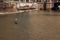 Two people in a St. Patricks Day decorated canoe with American flag as they pass by a construction site on the Chicago River