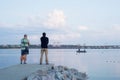 Two people stand on the pier near the city river. Against the background of a boat with fishermen, a tourist bridge Royalty Free Stock Photo