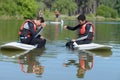 two people standup paddleboarding chating