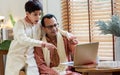 Two people of surprising Indian single father, son twearing traditional clothes, using laptop or notebook, win the game, playing