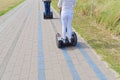 Two people traveling on Segways on paved path