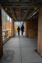 Two people walk under a construction structure in downtown Toronto, Ontario, Canada