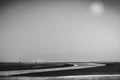 Two people walking on tidal sand bar on the beach as the tide goes out  with the tide running in a winding river across the beach Royalty Free Stock Photo