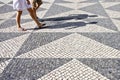 Two people walking in a typical Portuguese street paved in little stone Royalty Free Stock Photo