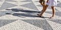 Two people walking in a typical portuguese street paved in little black and white stone (Portugal) Royalty Free Stock Photo