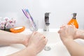 Two people wash their hands with soap under running water in white sink. close - up. antivirus protection wash your Royalty Free Stock Photo