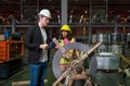 Two people wearing hard hats standing next to a large roll forming machine wheel in an industrial factory Royalty Free Stock Photo