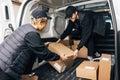 Two people working for delivery company unloading cardboard boxes from van