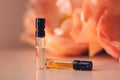 Two perfume samples with aroma water against peonies in soft focus. Face serum, essential oil