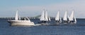 Two person sailboats in December regatta with large motorboat passing infront of them and bridge in background Royalty Free Stock Photo