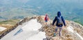 Two persons climbing down the high rocky and snowy mountain in North Macedonia