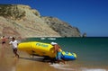 Two persons dragging at the beach an inflatable flyfish water attraction