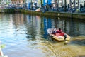 Two persons floating on the boat on the river Amstel in Amsterdam, The Netherlands