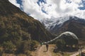 Two persons hiking towards Salkantay Mountain passing near sleeping domes camping