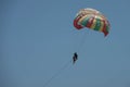 Two persons - man and child are parasailing. Colorful parachute, man holds from behind a child. Close up photo on clear blue sky Royalty Free Stock Photo