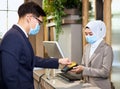 Two persons wearing anti-virus masks are paying by credit card. Accepting payments during the COVID-19 epidemic