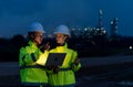 Two petrochemical workers or engineers discuss about work using laptop at night and stand in front of the factory with light Royalty Free Stock Photo