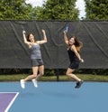 Two pickleball players jumping with paddles