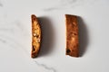 Two Pieces of Almond and Cranberry Biscotti Standing on Marble Counter, Shadowed with Natural Light