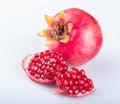 Two pieces of a beautiful young juicy pomegranate in a beautiful peel with beautiful bright pomegranate seeds and a whole pomegran