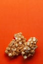 Two pieces of Chickpea (chana dal) chikki on orange background.