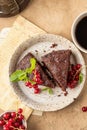 Two pieces of chocolate cake brownie decorated with red currant berries and mint for coffee on beige textured background Royalty Free Stock Photo