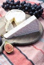 Two pieces of French soft cheeses Brie and Camembert with white mold and strong odor, served with fresh ripe figs and black grapes Royalty Free Stock Photo