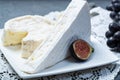 Two pieces of French soft cheeses Brie and Camembert with white mold and strong odor, served with fresh ripe figs and black grapes Royalty Free Stock Photo