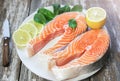 Two pieces of fresh salmon steak on a white plate with spinach and lemon, on  a gray wooden background. Omega 3 vitamin, healthy Royalty Free Stock Photo