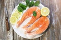 Two pieces of fresh salmon steak on a white plate with spinach and lemon, on  a gray wooden background. Omega 3 vitamin, healthy Royalty Free Stock Photo