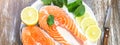 Two pieces of fresh salmon steak on a white plate with spinach and lemon, on  a gray wooden background. Omega 3 vitamin, healthy Royalty Free Stock Photo