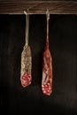 Two pieces of Fuet hanging in front of a rustic wall. Traditional sausage of Catalonia, Spain.