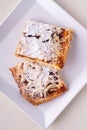 Two pieces of homemade cookies apricot jam powdered sugar in white square plate