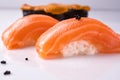 Two pieces of Japanese salmon nigiri sushi, piece of uni gunkan on a white reflective surface decorated black tobiko. Close up. Royalty Free Stock Photo