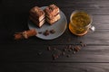 Two pieces of multi-layered honey cake on a plate, on a black wooden background with a cup of tea, chopsticks and coffee Royalty Free Stock Photo