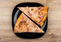 Two pieces of pizza in black plate on wooden table Royalty Free Stock Photo