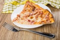 Two pieces of pizza in plate, fork and yellow napkin Royalty Free Stock Photo
