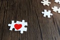 Two pieces of puzzle forming red heart on wooden, heart on pieces of jigsaw, romantic background for Royalty Free Stock Photo