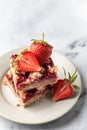 Two pieces of Strawberry granola bars on a pate on white marble background close up. Delisious homemade oat squares for