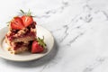 Two pieces of Strawberry granola bars on a pate on white marble background close up. Delisious homemade oat squares for