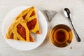 Pieces of shortcrust pie with apricot jam in plate, tea bag, spoon, cup with tea on wooden table. Top view Royalty Free Stock Photo