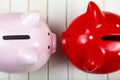 Two pigs piggy banks on a white wooden background