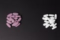 Two piles of pills lie on a black background. white and purple. choice. addiction.