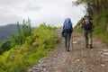 Two pilgrims on Camino de Santiago. Couple of tourists on the hill. Man and woman with backpack and sticks walk in mountains. Royalty Free Stock Photo
